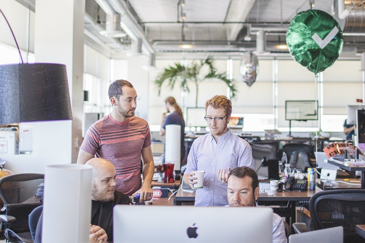 Adam Polselli and Rasmus Andersson chat with Morgan Knutson and Ryan Putnam. Each new hire receives a helium-inflated Dropbox balloon (silver for interns, green for longer-term hires) indicating that they are new to the company.